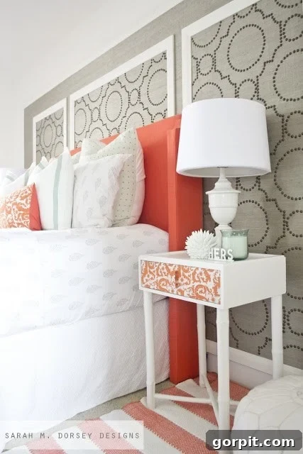 Colorful yet calm master bedroom by Sarah M. Dorsey Designs, showcasing extensive DIY projects, a soothing palette with coral accents, and luxurious grass cloth with nailhead details.