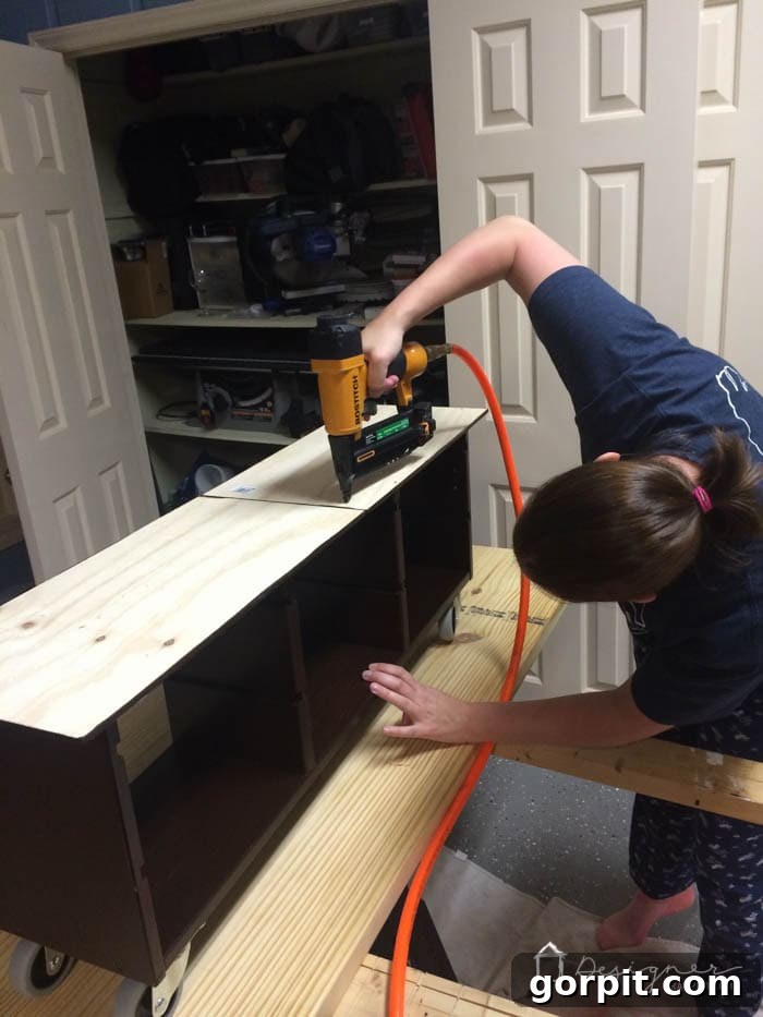 Plywood tabletop being aligned and glued to the top of the Ikea Trofast storage unit, with slight overhang on the sides.