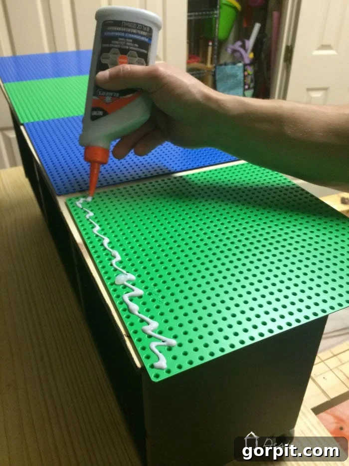 Four Lego base plates glued onto the plywood tabletop, with heavy objects placed on top to ensure a strong bond while drying.