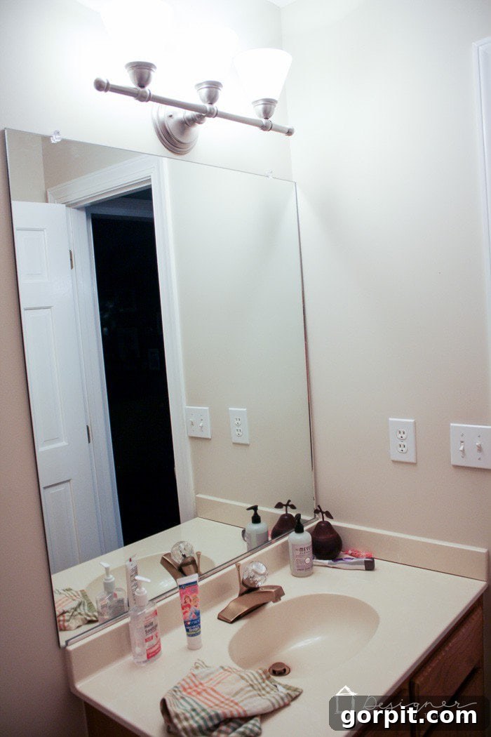 Before: Outdated cultured marble vanity and builder-grade mirror in a powder room.