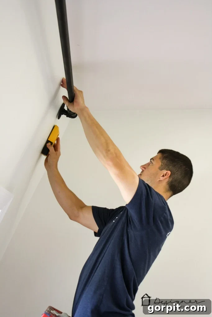 Marking drilling points on the wall using the floor flange for installing the DIY pipe curtain rod.