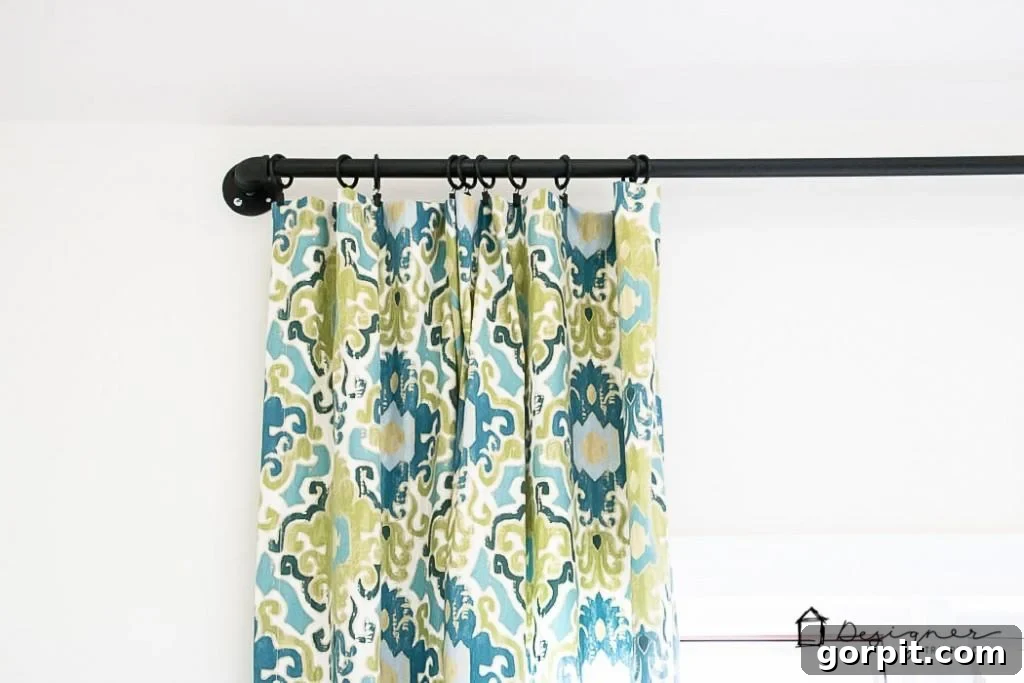 Attaching curtains to the drapery rings on the newly installed DIY industrial pipe curtain rod.