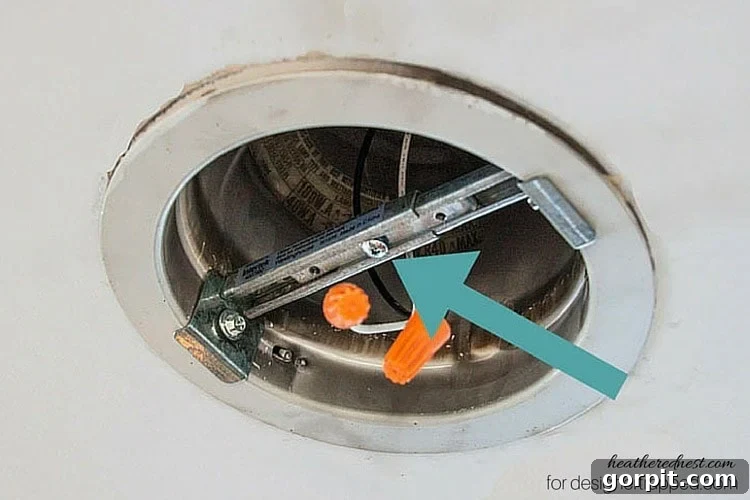 Adjusting and securing the cross bracing inside the recessed light housing for a stable base.