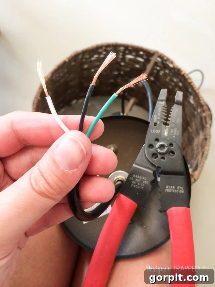 Instant Glow: Beginner-Friendly DIY Lighting 5 Close-up image of hands using electrical wire cutters to strip insulation and expose copper wire for the DIY pendant light.