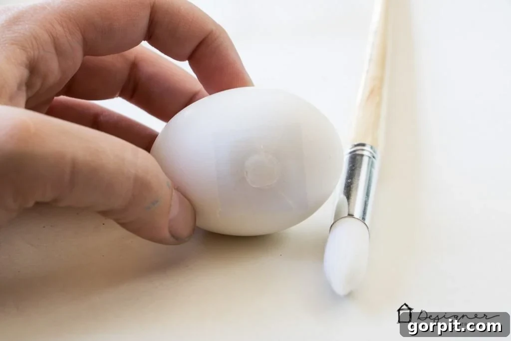 Carefully placing adhesive glue dots on a hard-boiled Easter egg for a creative design.