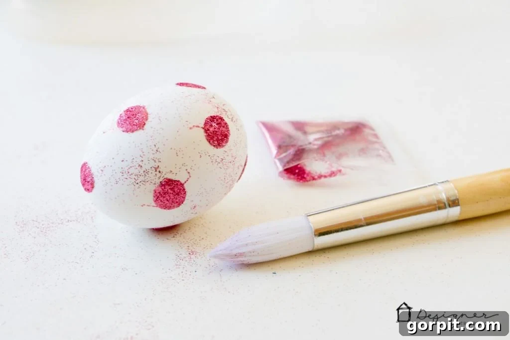 Another angle of the glitter application process on a festive Easter egg.