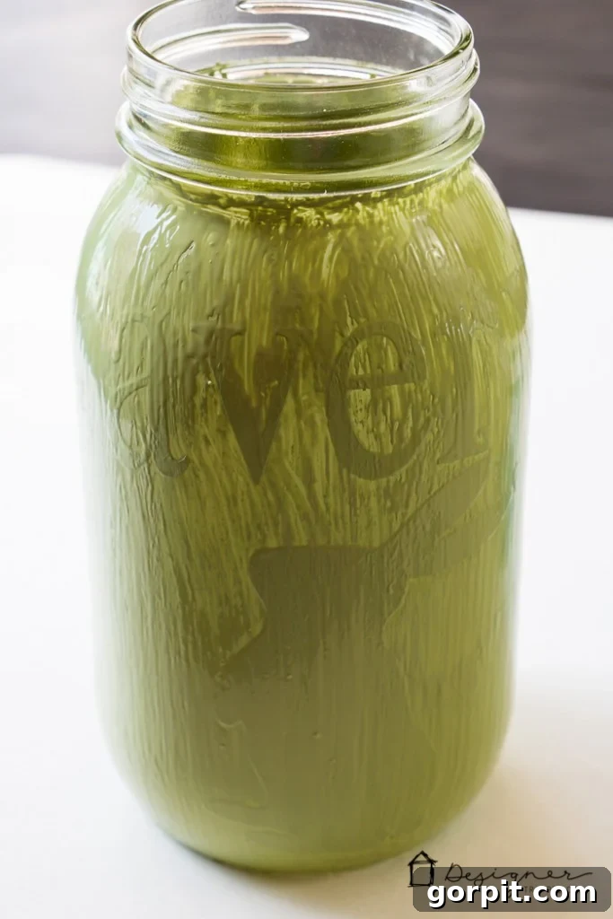 The second coat of chalk paint applied to a mason jar, fully covering the vinyl stencil, ready for drying and peeling.