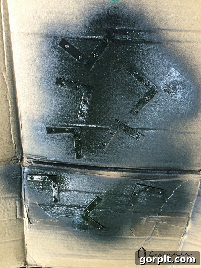 Flat corner braces after painting black, ready for assembly on a DIY picture frame.