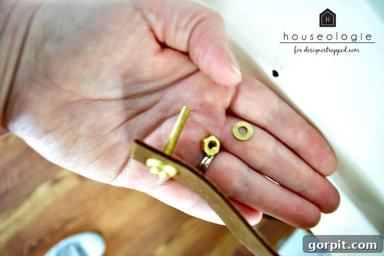 Handcrafting Leather Drawer Pulls for Custom Furniture 5 photo of brass screws and nuts and a strip of leather in a woman's hand