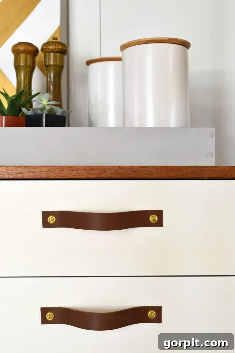 Handcrafting Leather Drawer Pulls for Custom Furniture 7 close up photo of leather drawer pulls with brass screws on modern white drawer fronts