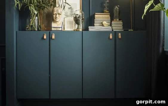 Dark green built-ins against a dark green wall, made from IKEA Ivar cabinets. Books, plants, and art adorn the credenza. 