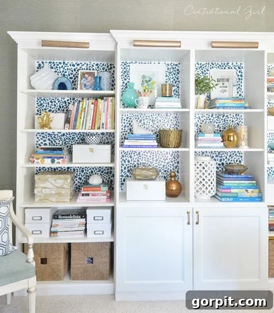 Besta and Billy bookcases from IKEA include lower cabinet doors and gold light fixtures on the top. Behind the books and knickknacks on the shelves is a graphic polka-dot backing. 