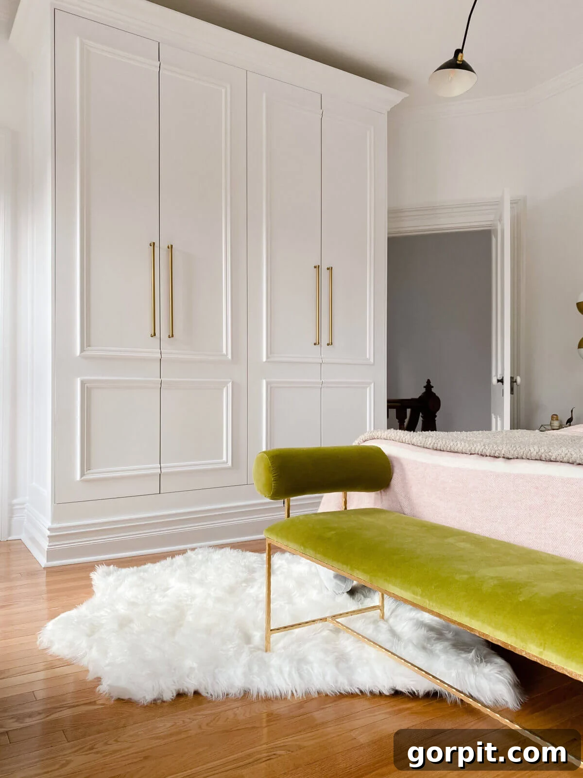 Two Pax wardrobes made into closets in a bedroom with a green bench seat in front of the bed. 