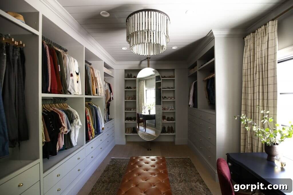 A large closet the size of a small room is lined with built-ins made from IKEA Pax shelves and drawers.  Clothes hang from every open shelf. 