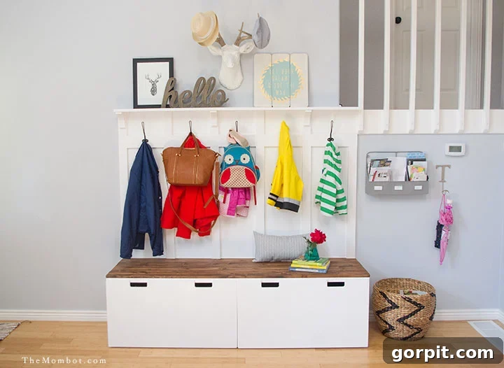 A mini-mudroom for children includes an IKEA Stuvas unit, lower hooks with coats and bags hung above a bench with large square storage bins underneath.