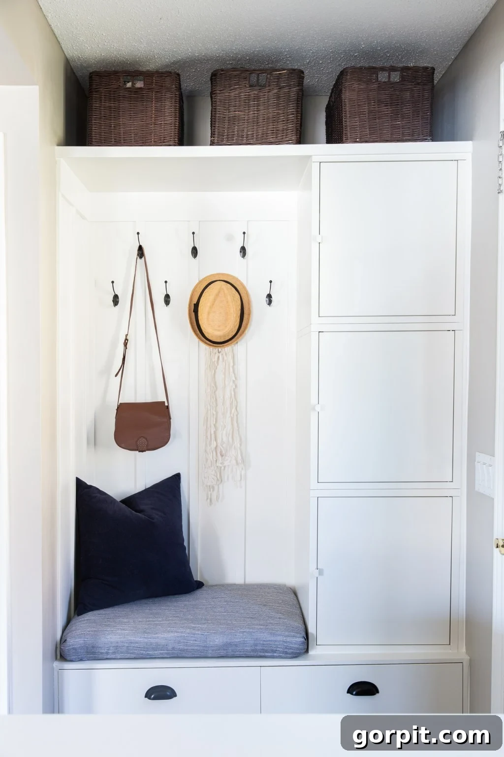 This DIY IKEA hack uses Besta and Hallan units to create a bench and cabinets along the side wall. Bins line the top shelf, while hooks behind the bench hold a hat and purse. 