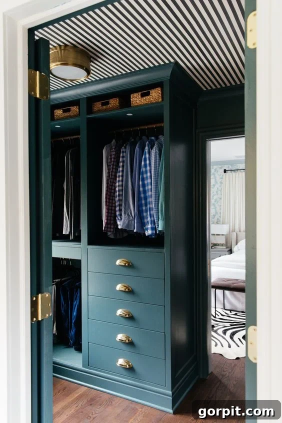 A dark green custom closet is made from DIY IKEA hacks using Pax shelves and drawers. The shelves have hanging clothes above deep drawers on the bottom. 