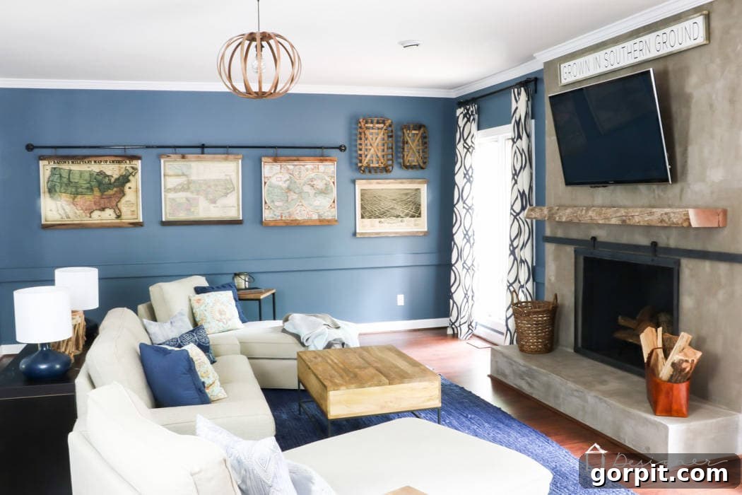 View of the living room featuring reclaimed wood map frames on an industrial pipe above a newly updated fireplace with a barn door style screen, creating a cohesive industrial-rustic look.