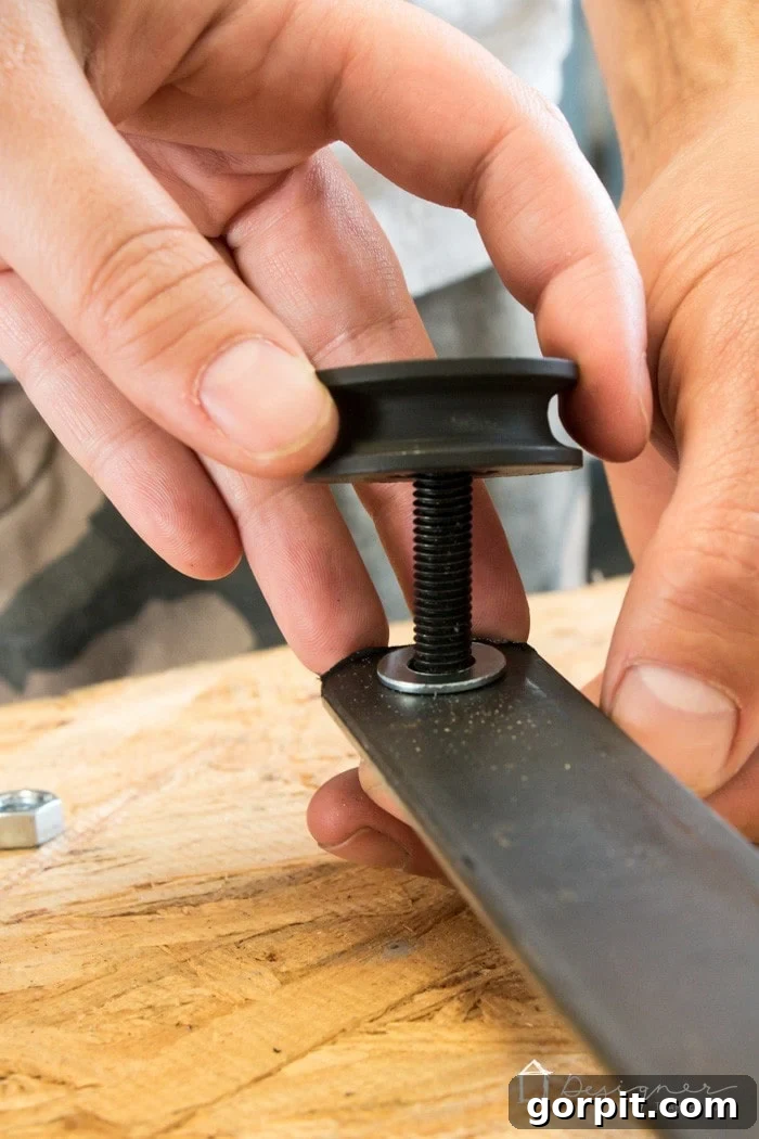 Attaching the pulley wheels to the wheel posts for the sliding mechanism of the fireplace screen.