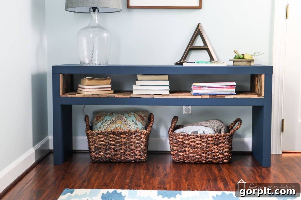 IKEA Lack Transformation: Designer Style for Less 2 A beautifully customized IKEA Lack sofa table, painted in a sophisticated blue with an inner shelf lined with wood mosaic tiles, positioned next to a door and adorned with books and decorative baskets.