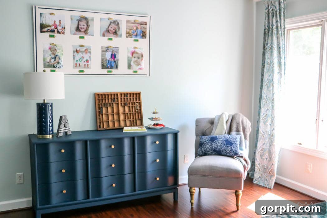 Wood Wonders: Your Guide to Transforming Furniture with Paint 13 A bright room corner with a painted blue wood dresser with gold knobs, styled with books and decor, next to a gray chair by a sunlit window. A collage of children's photos hangs above, showing how to paint wood furniture to enhance a family space.