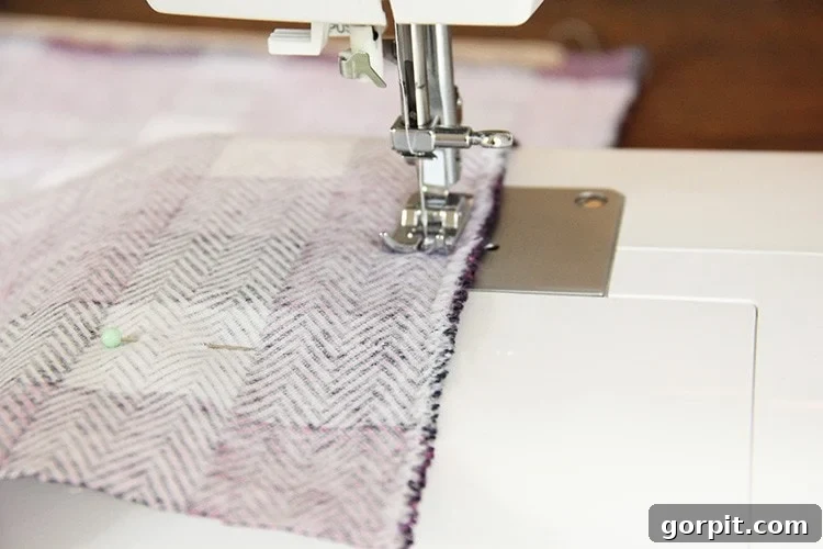 Sew Your Own Zippered Pillow Cover 13 A sewing machine stitches the final three edges of a pillow cover, demonstrating the closing steps of the project.