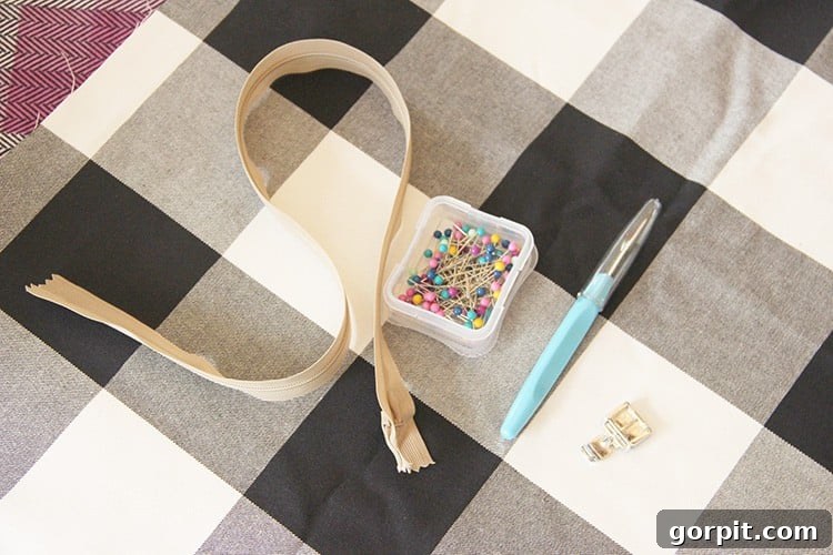 Sew Your Own Zippered Pillow Cover 3 A flat lay photograph displaying essential sewing supplies: fabric swatches, a zipper, and straight pins, neatly arranged for making a zippered pillow cover.