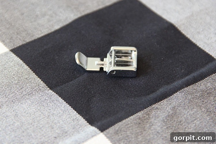Sew Your Own Zippered Pillow Cover 7 A close-up view of a sewing machine's specialized zipper foot, ready for attachment and use in sewing projects.