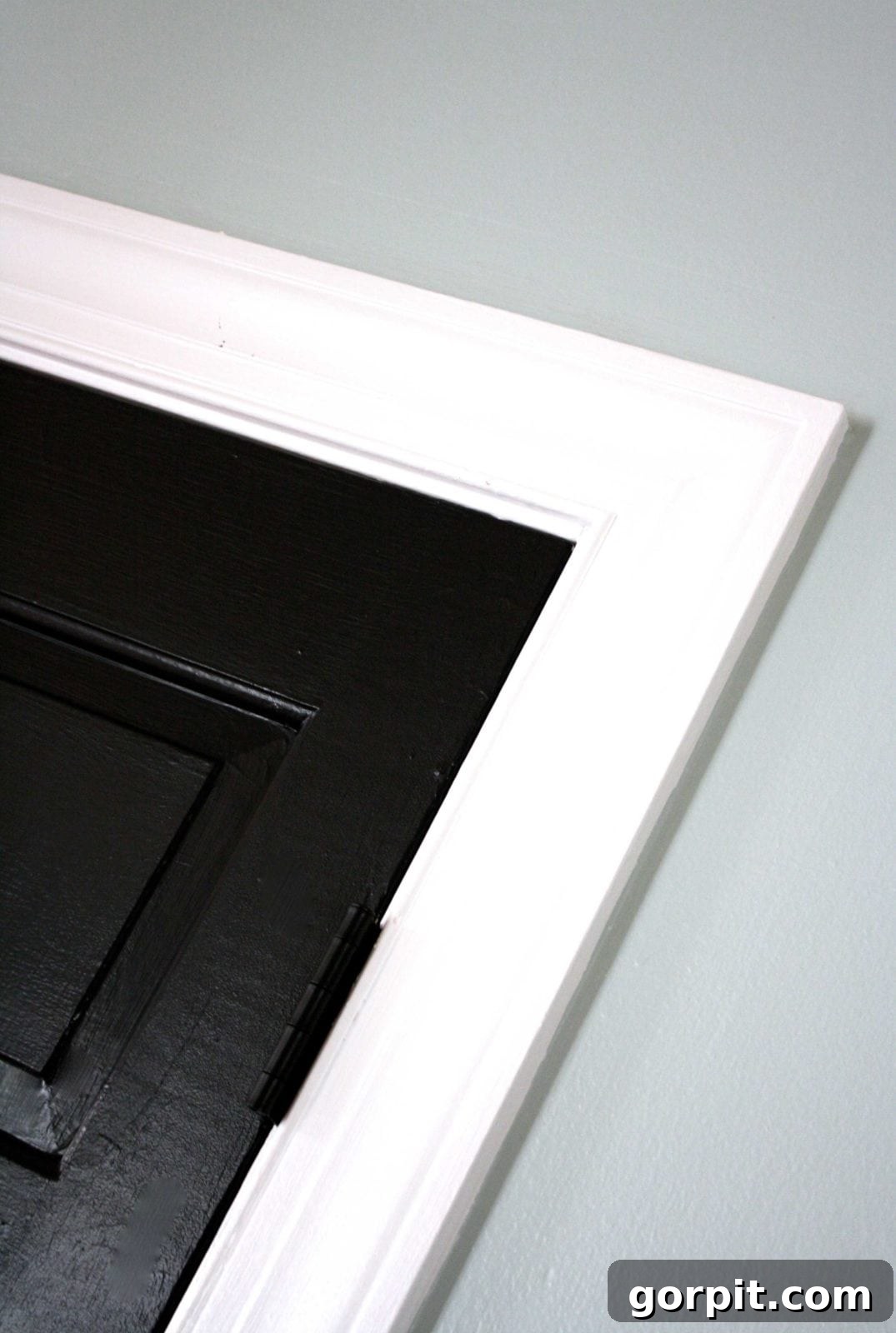 A close-up of the corner of the pantry door trim which has been painted a shockingly bright white, which compliments the black doors.