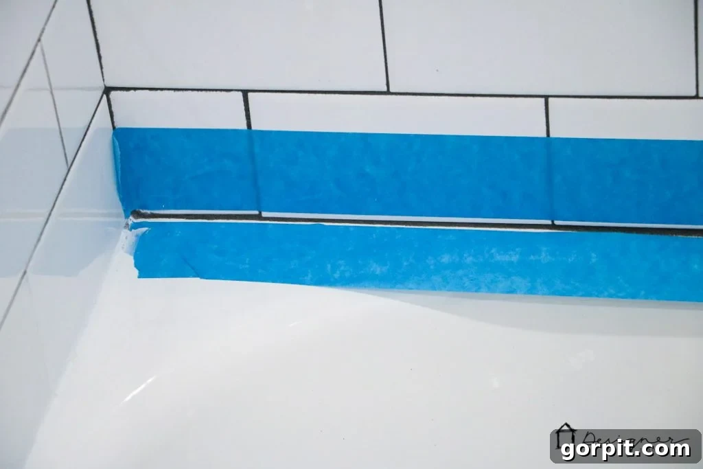 Use painter's tape to create perfectly straight lines when caulking a bathtub, making the process easier and ensuring a professional finish for your bathroom DIY project.
