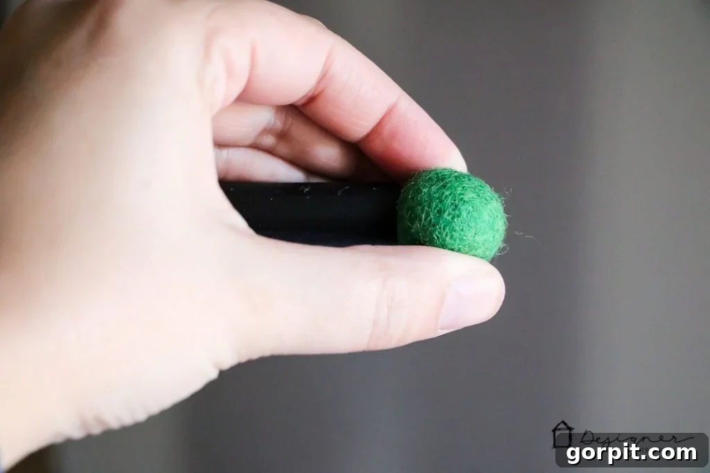 Adding green felt balls to the dowel ends for a decorative finish