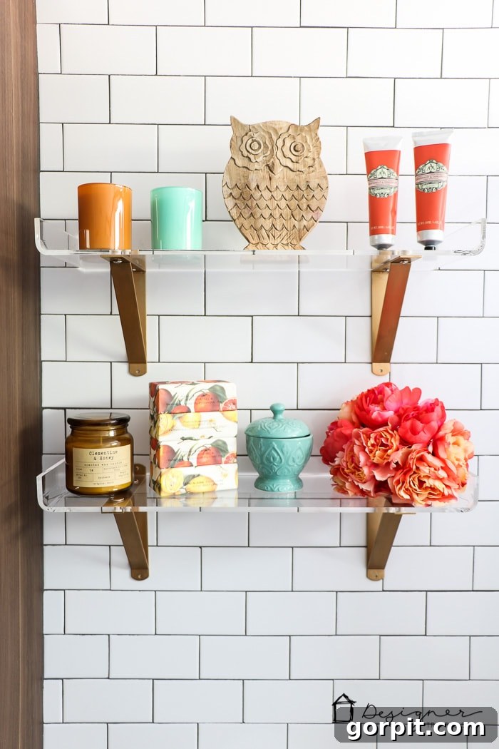 Detail shot of lucite shelves against floor-to-ceiling subway tile in a contemporary DIY bathroom.