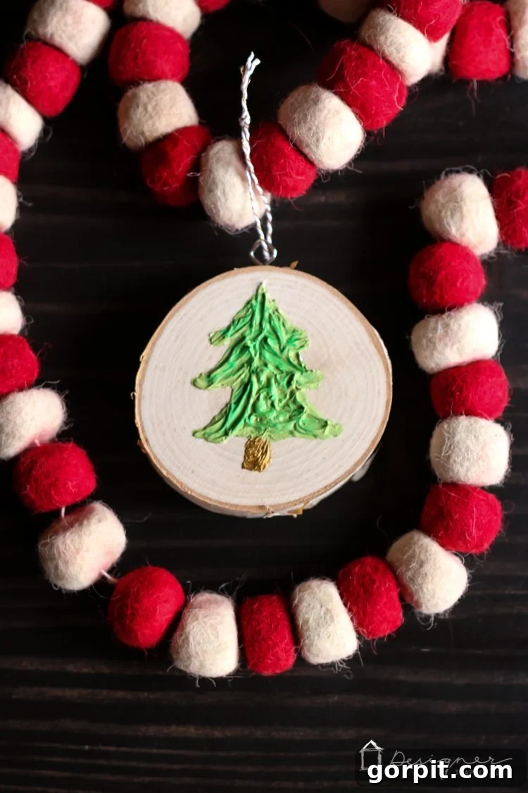 A vertical shot of the finished DIY textured Christmas ornament, emphasizing its elegant shape and intricate caulk detail.