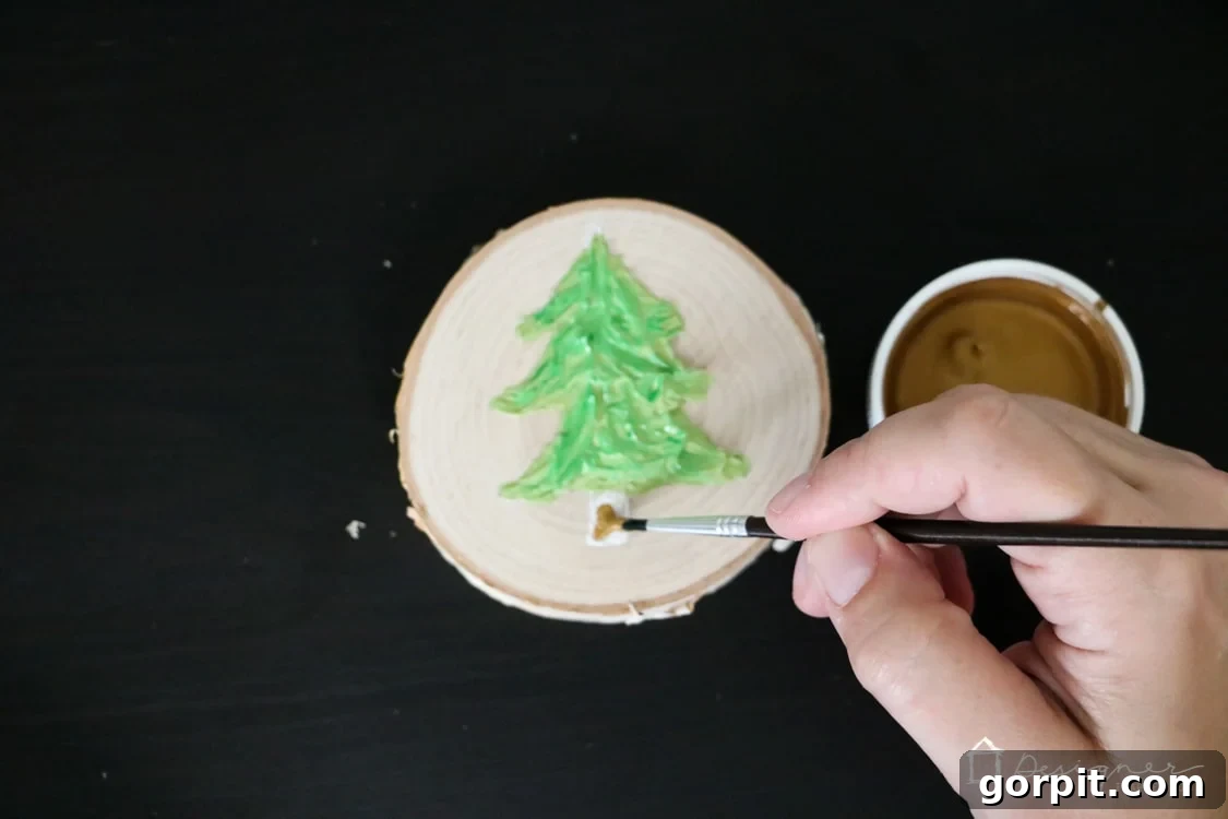Close-up of the painted caulk Christmas tree ornament, highlighting the contrasting gold metallic paint used for the tree trunk.
