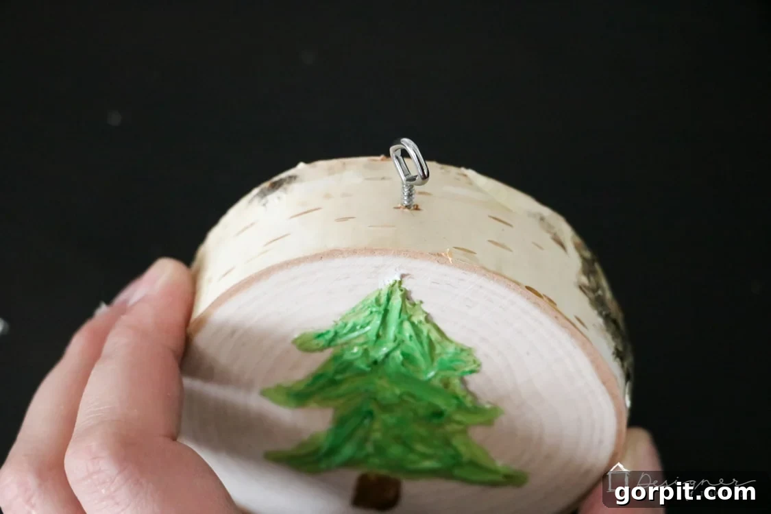 A finished textured caulk ornament with a small screw eye inserted at the top and baker's twine looped through, ready for hanging.