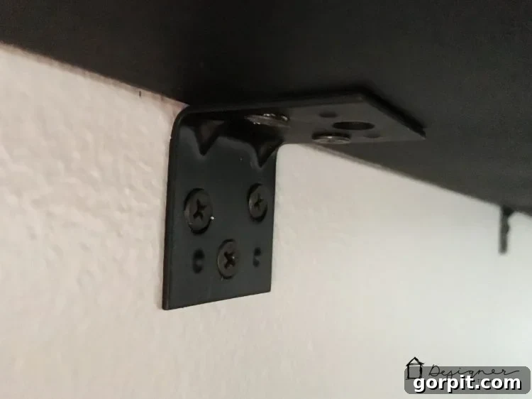 Effortless Pipe Desk DIY 10 A close-up of a right-angle bracket securing the DIY pipe desk to the wall, demonstrating the strong, stable attachment point.