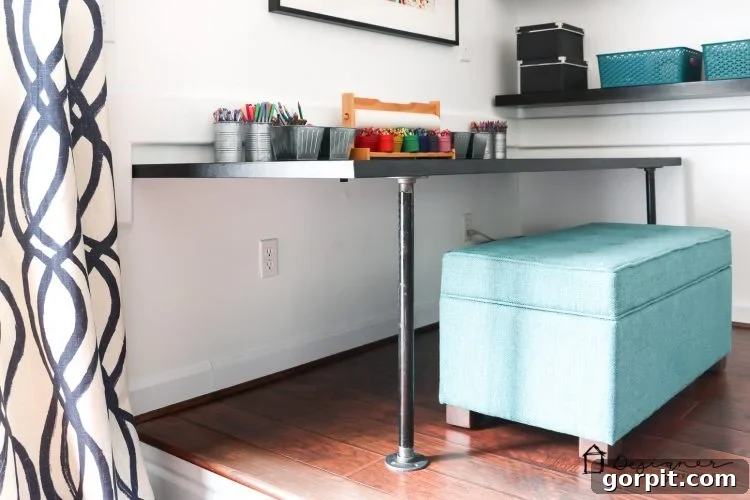 Effortless Pipe Desk DIY 14 Colorful close-up of the storage ottoman with bright cushions next to the DIY pipe desk, ready for kids' activities.