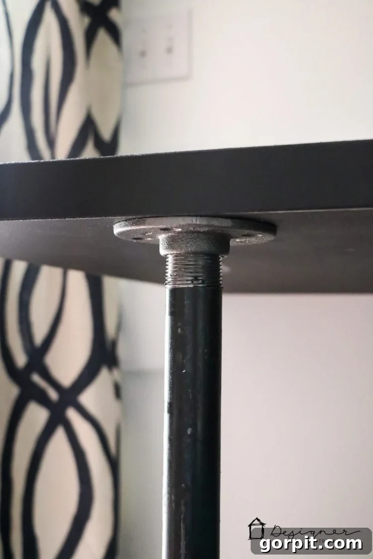 Effortless Pipe Desk DIY 19 Detail shot of the industrial pipe legs and floor flanges, showcasing the sturdy base of the DIY desk.