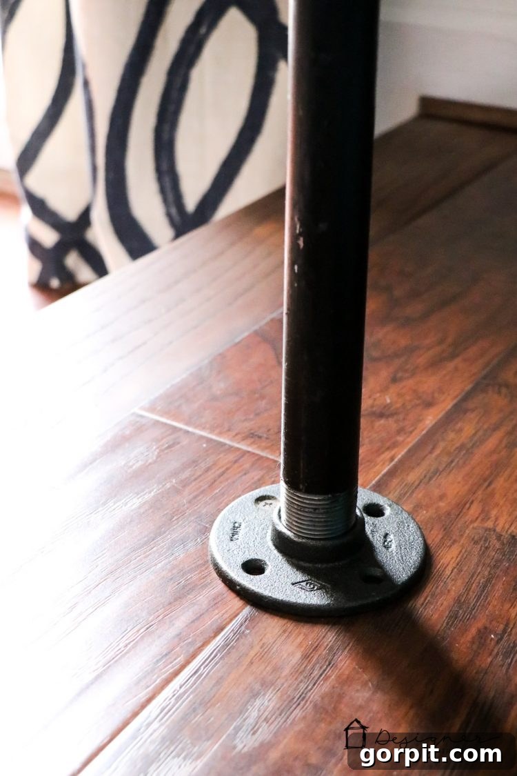 Effortless Pipe Desk DIY 20 Securely fastened industrial pipe desk leg with a screw drilled into the floor for enhanced stability, a crucial safety feature for kids.