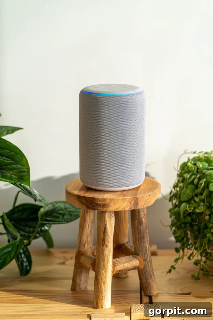 A tall Amazon Alexa Echo Smart home device on a miniature wooden stool surrounded by plants. 