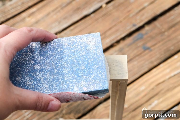Applying wood putty to nail holes on a newly constructed DIY frame, a crucial step before sanding and staining.