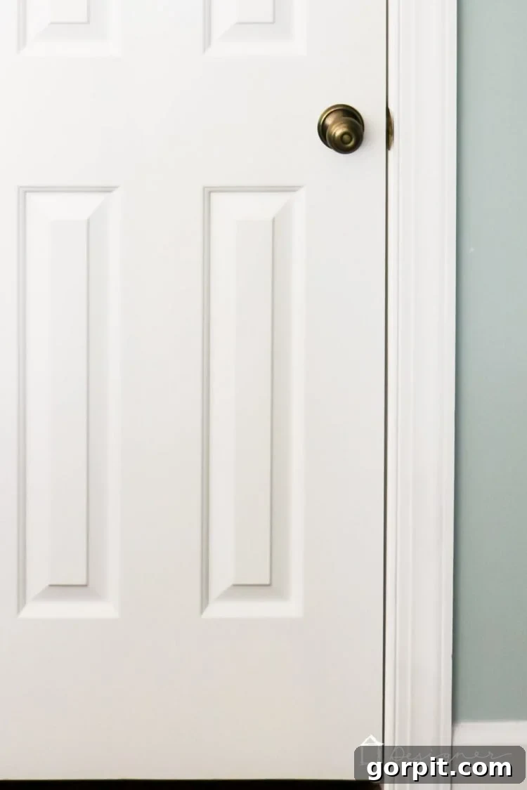 Before: Another view of an interior door with old brass hinges and yellowed paint.
