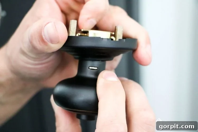 Close-up of installing Schlage Andover style door knob in Aged Bronze finish on black door.