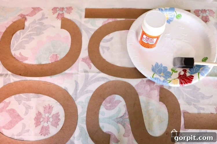 Adhere fabric to chipboard letters with Mod Podge and press flat to prevent curling.