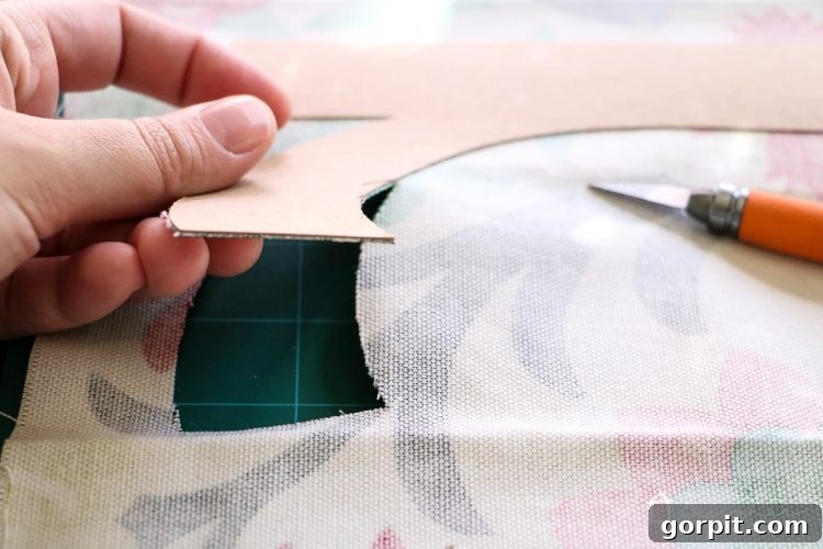 Use an Exacto knife for precise cutting of fabric around chipboard letters.