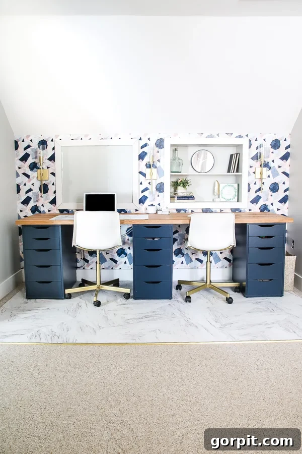 Smart IKEA Desk Upgrades for Less 15 An IKEA desk hack featuring navy drawers, a natural wood countertop, and built-in shelves on a wall with blue-patterned wallpaper under an attic roof slope.