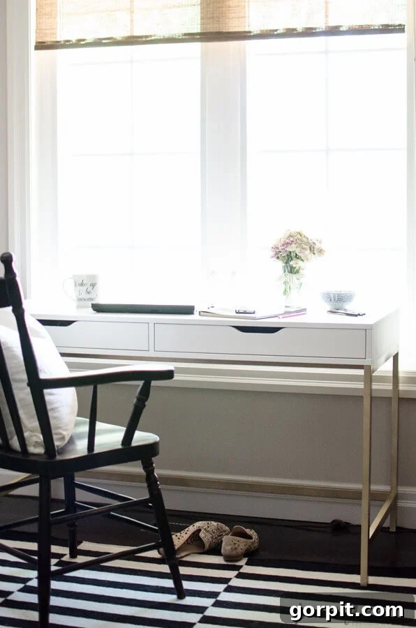 Smart IKEA Desk Upgrades for Less 7 A slim white desk with two under-mounted drawers provides a work area that takes up little space. A wooden black chair and slippers on a black and white rug complete this IKEA desk hack.