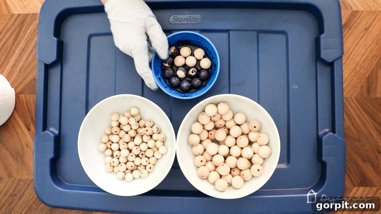 Wood beads soaking in a bowl of vibrant blue stain during the DIY curtain tie back project.