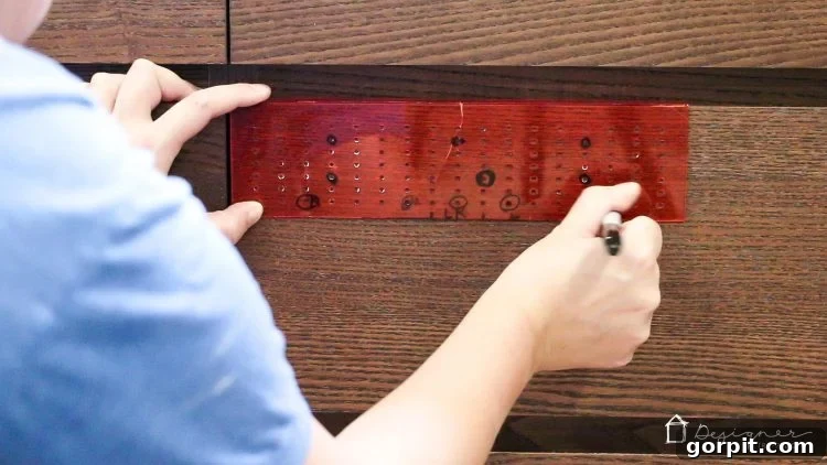 Close-up of an Ikea Malm drawer front with pencil marks indicating the precise placement for two new drawer pulls.
