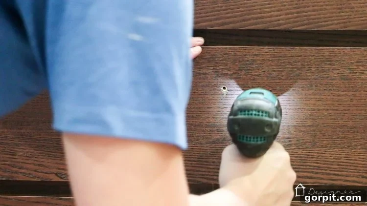 A drill driver is used to make pilot holes for the new drawer pulls on an Ikea Malm drawer front.